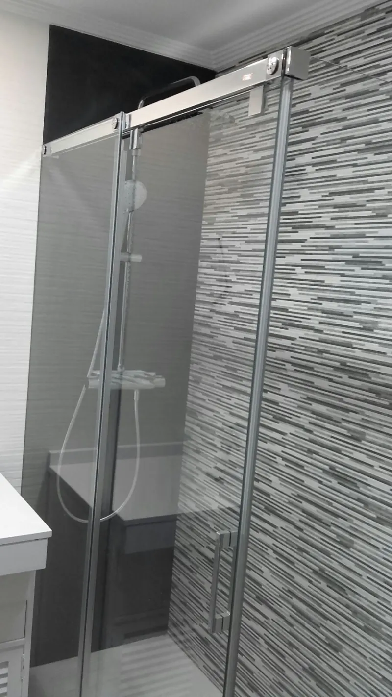 Baño con mampara corredera y revestimiento gris — Baños y cocinas por Reformas Monroy