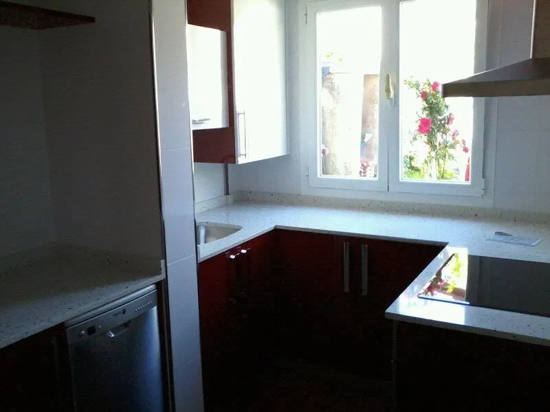 Cocina en granate con encimera blanca — Baños y cocinas por Reformas Monroy